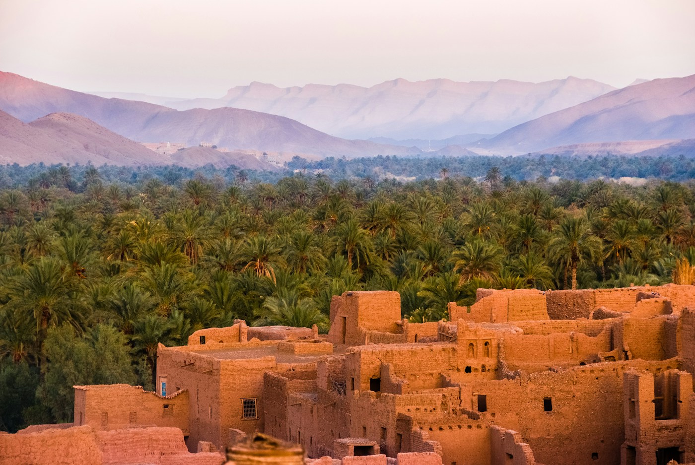 Earthen Moroccan buildings, palm trees and mountain scenery
